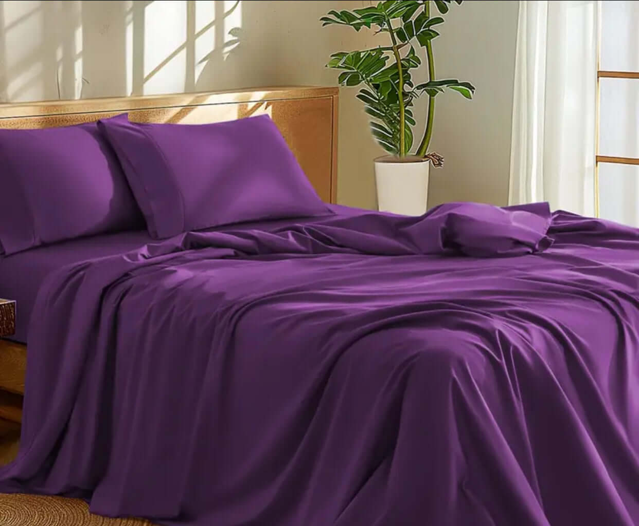 100 Percent Washed Cotton Sheet Set in rich purple color on a bed with natural light and a potted plant.